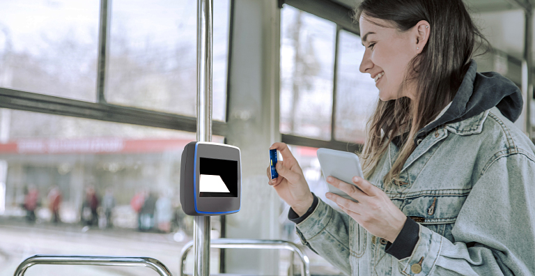 A woman on a bus tapping a card to a ticket reader