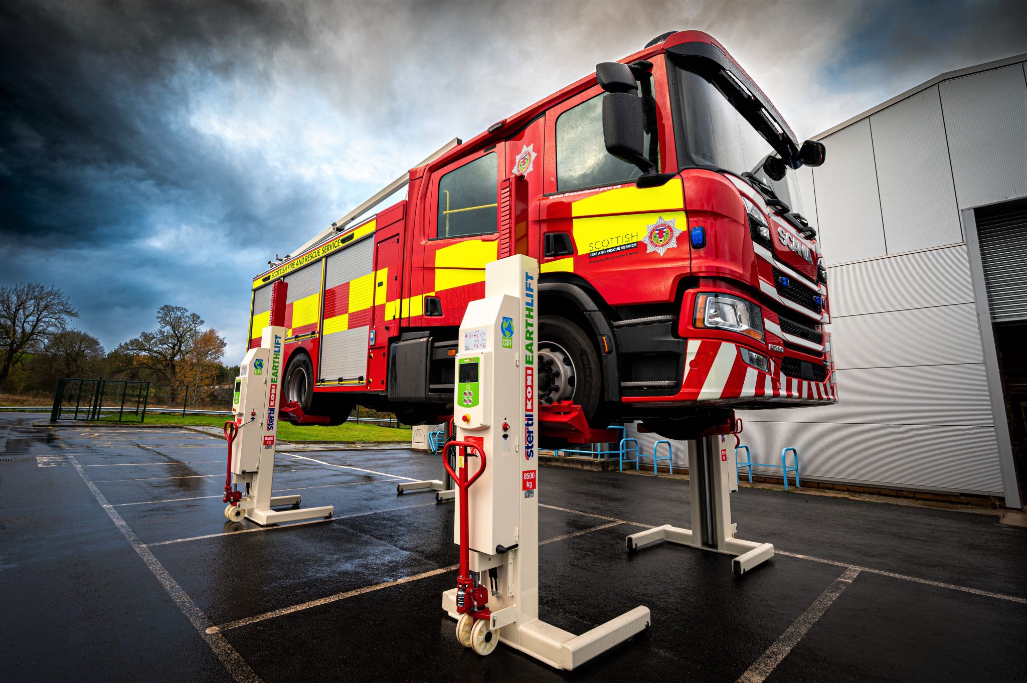 Red and yellow fire engine lifted mid-air by 4 mobile column lifts