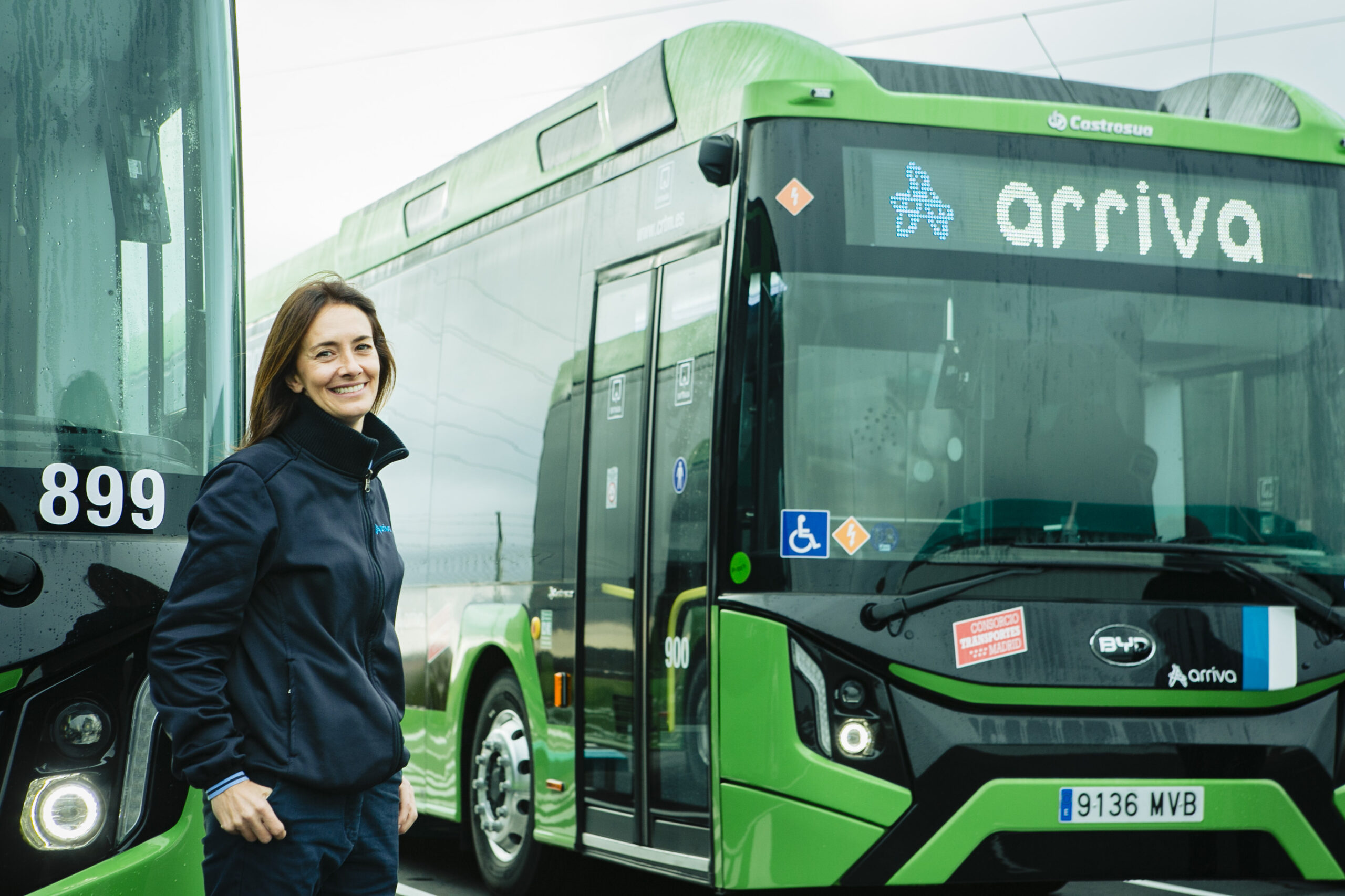 A woman smiling in front of a green Arriva bus