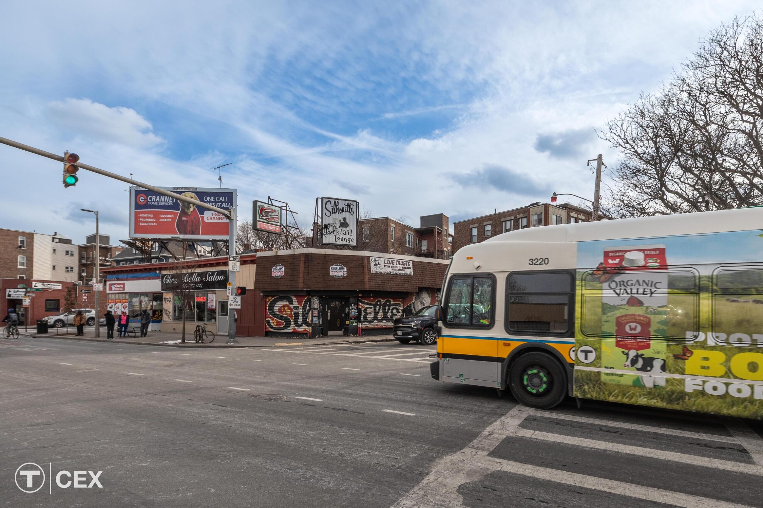 An MBTA bus approaches a green light as it travels through the intersection along Brighton Avenue at Allston Street