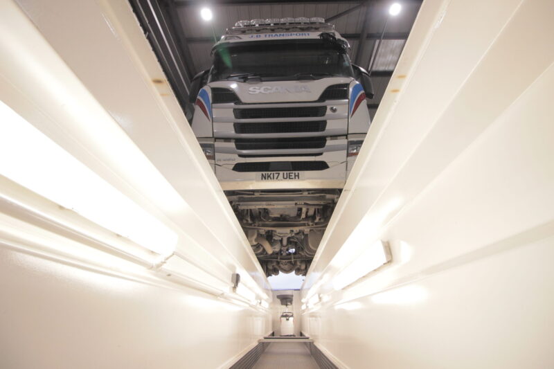 Scania truck over a vehicle inspection pit in a maintenance facility for servicing and repairs.