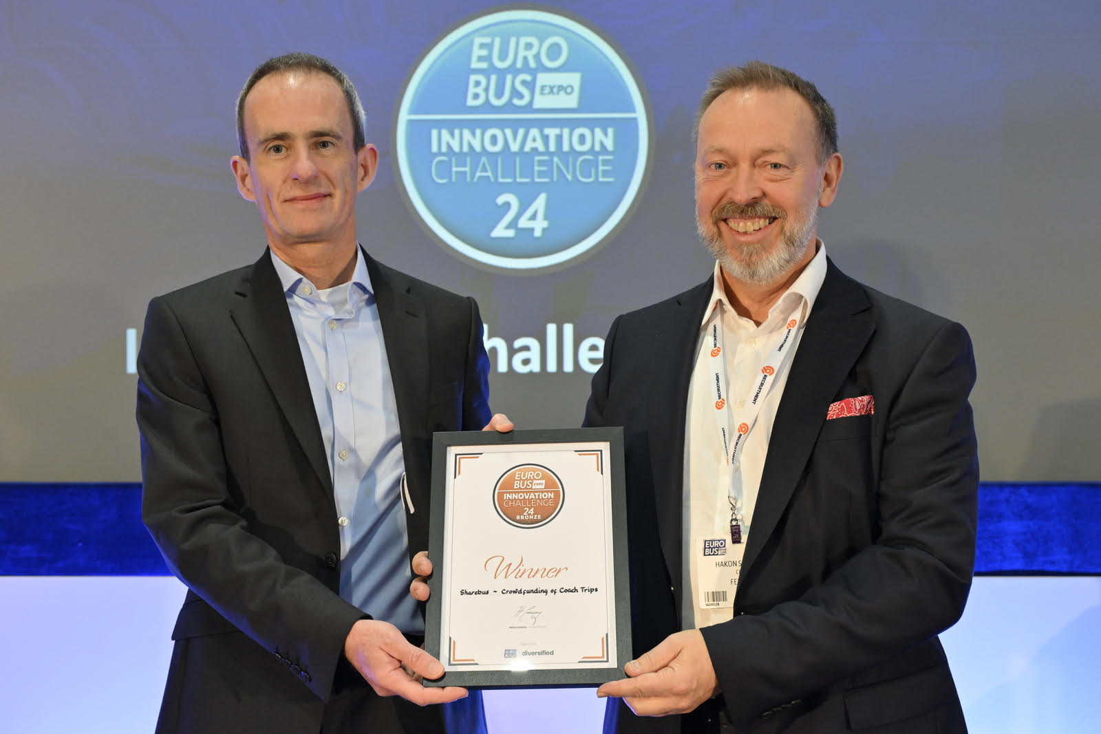 Two men wearing suits holding a certificate between them