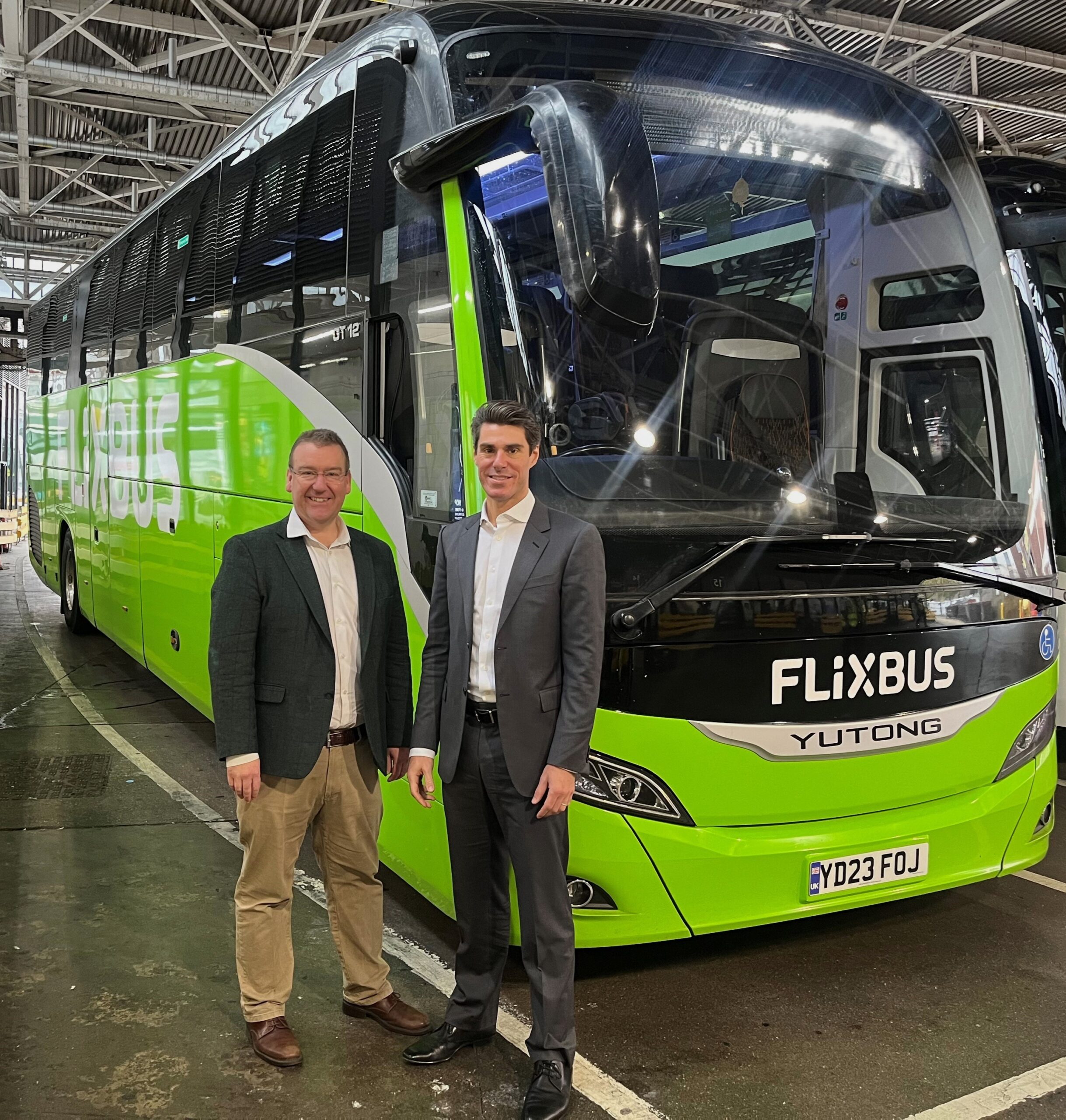 Two men stood beside a green FlixBus vehicle