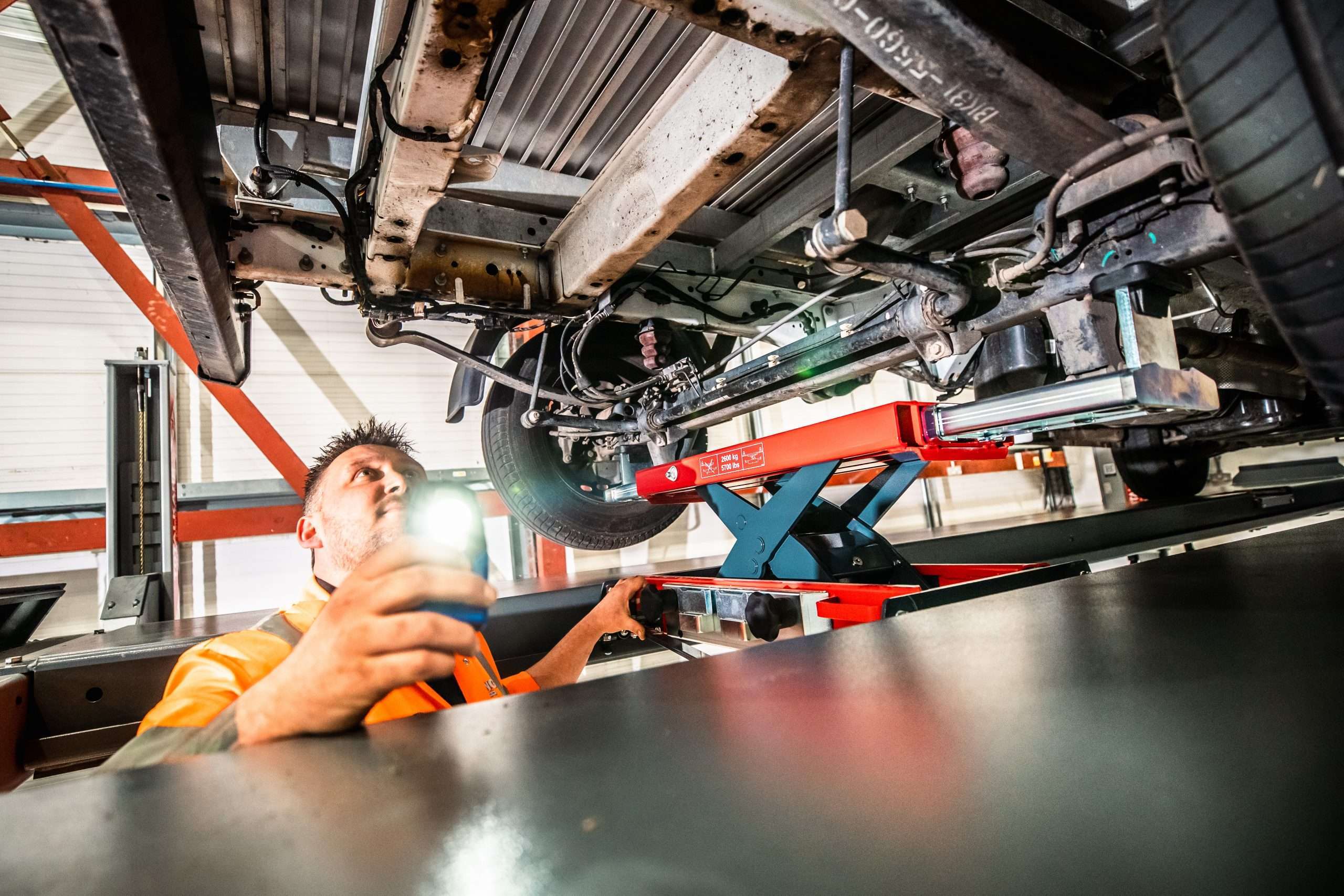 A man working on the underside of a vehicle which has been lifted into the air
