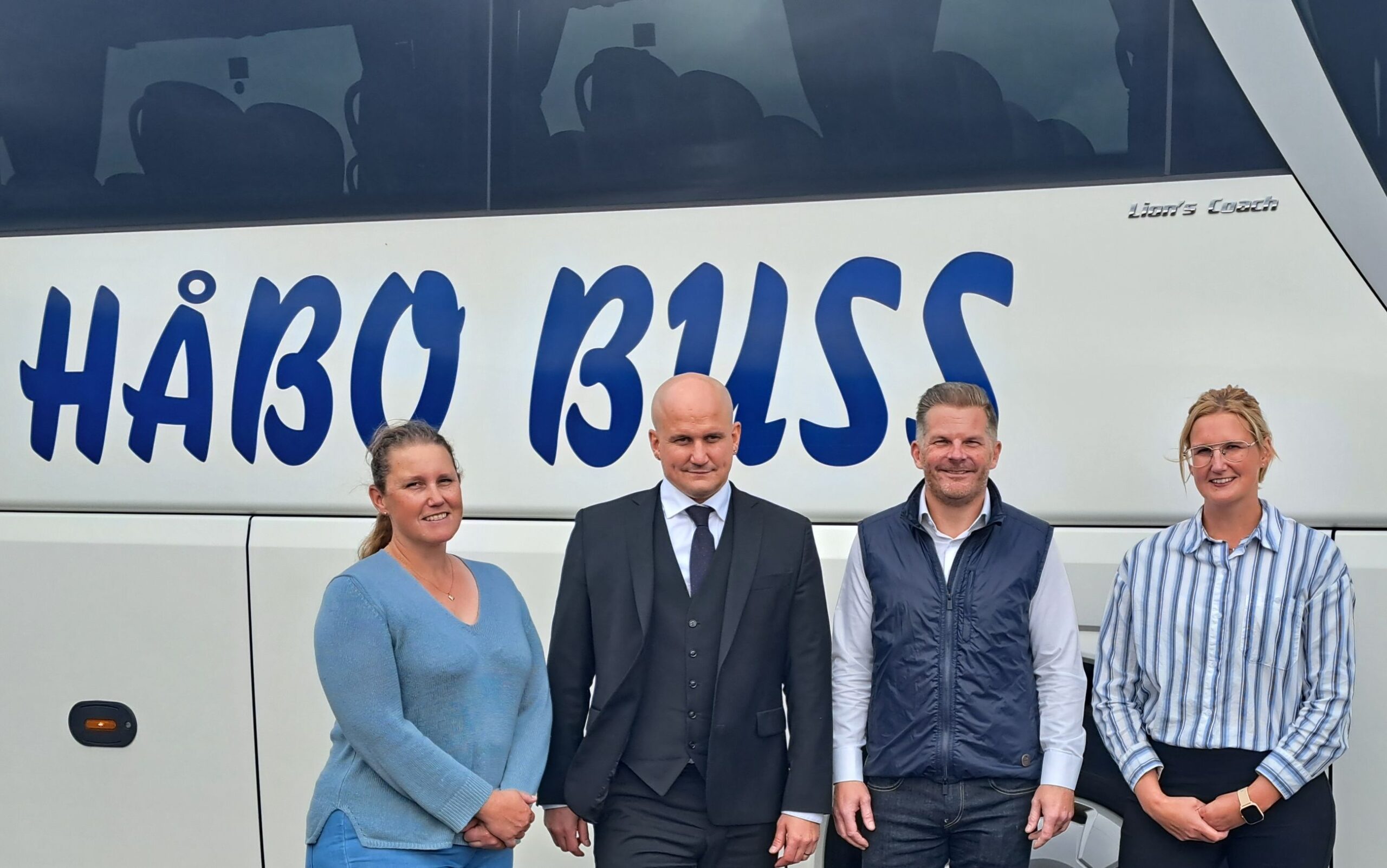Three people stood in front of a Håbo bus