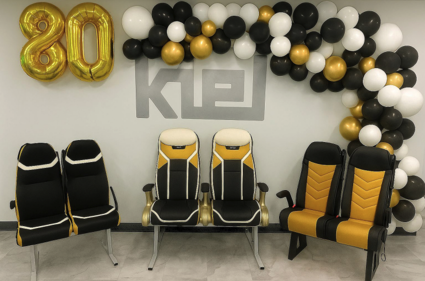 Black, white, and gold balloons to celebrate 80 years of Kiel, with 4 of its bus seating designs in the foreground