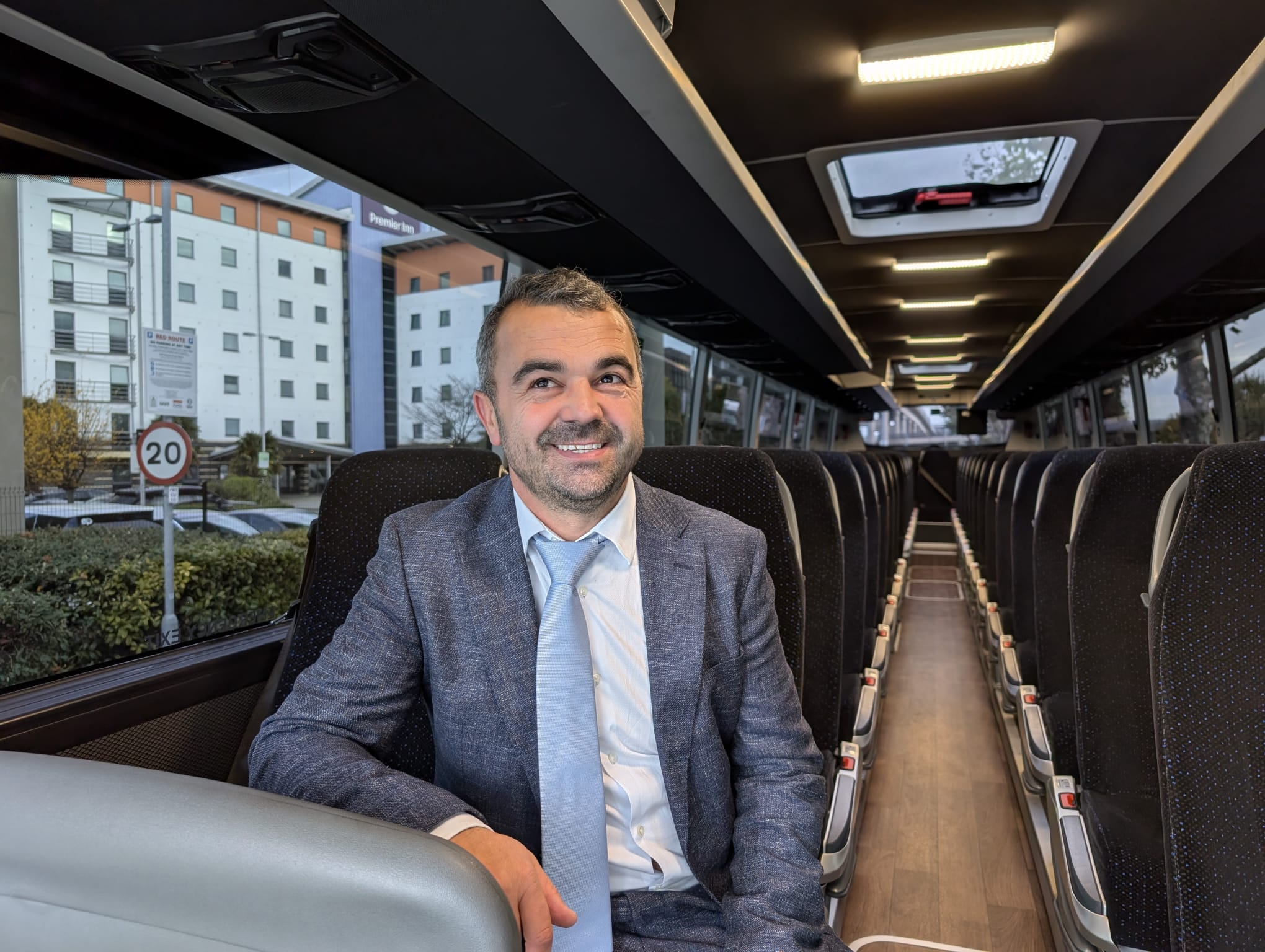 A smiling man sat on a bus