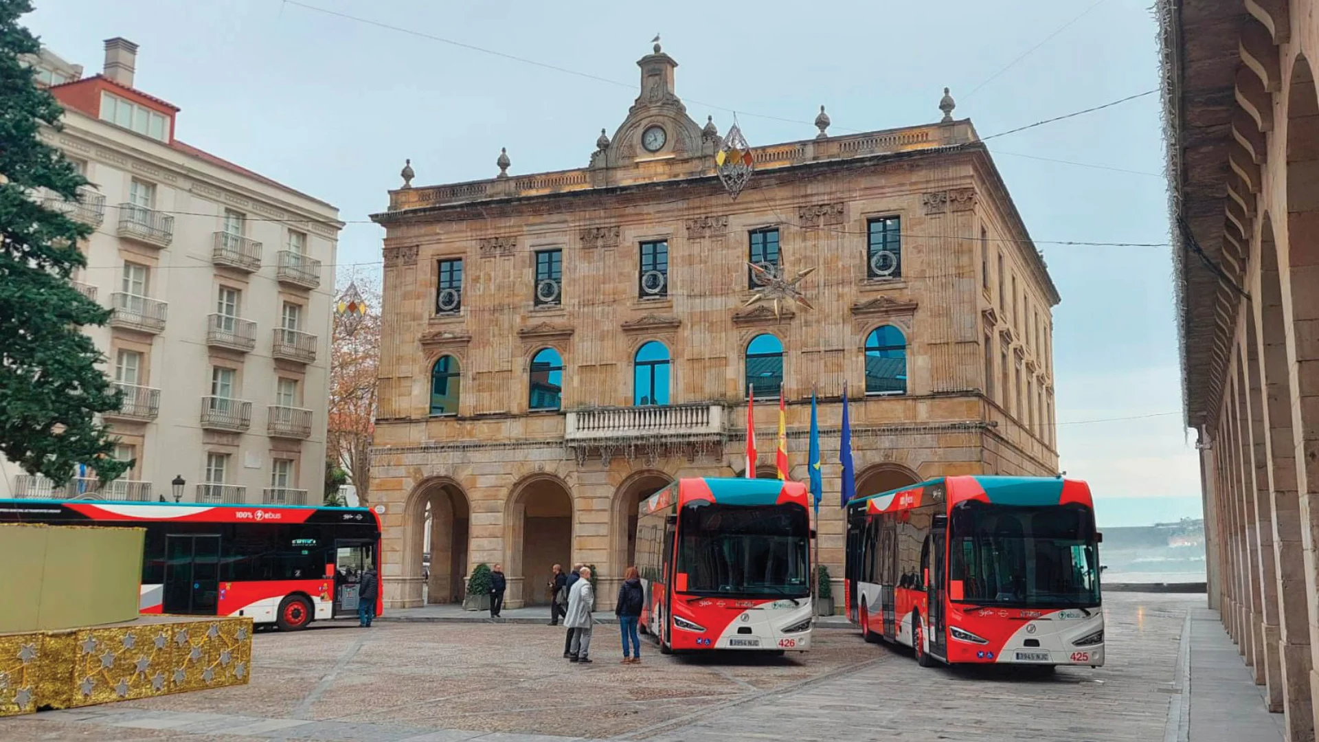 A set of red buses in front of an old building