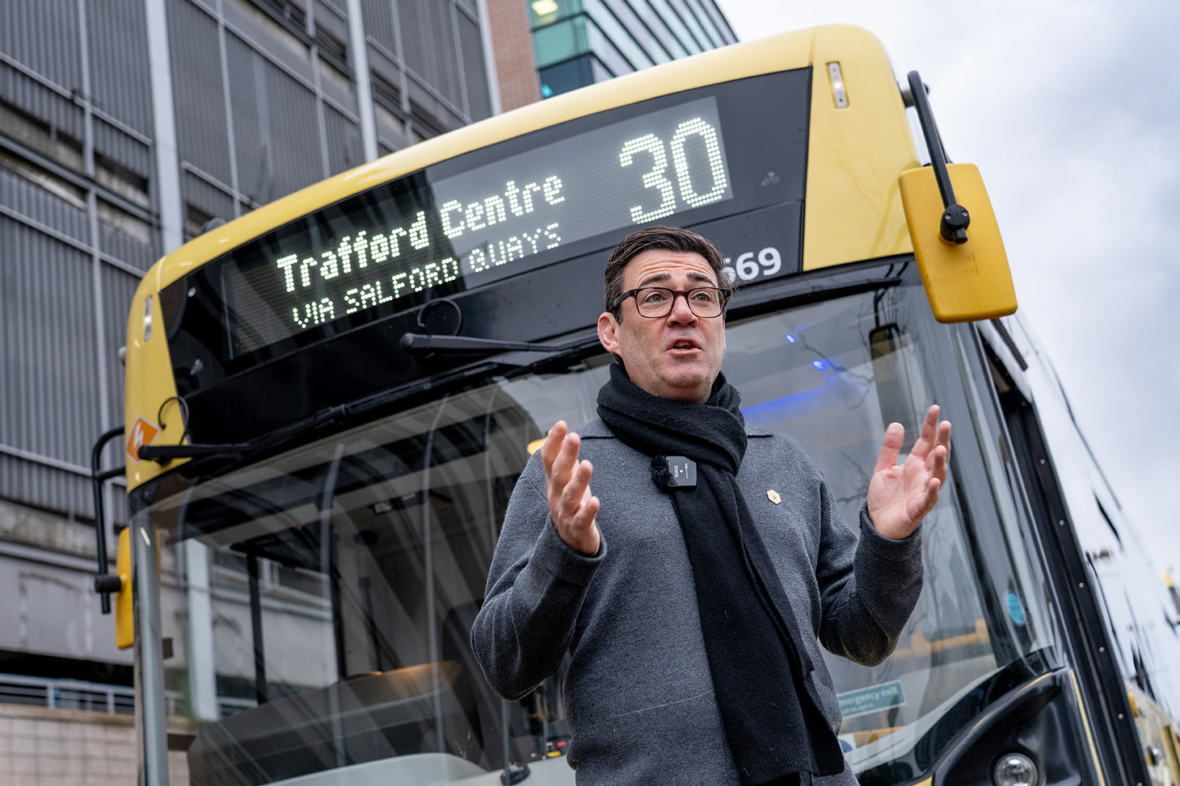 Mayor Andy Burnham in front of a yellow Bee Network bus
