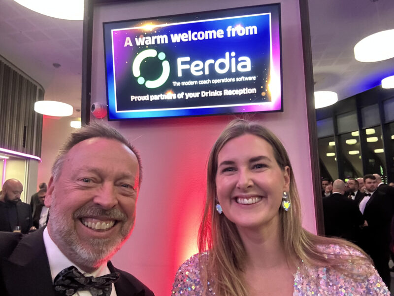 Photo of people in front of TV with Ferdia sponsoring the Drinks Reception imagery on it. 