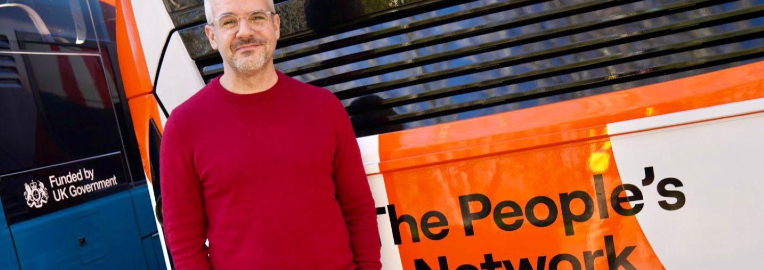 A man stood in front of an orange bus