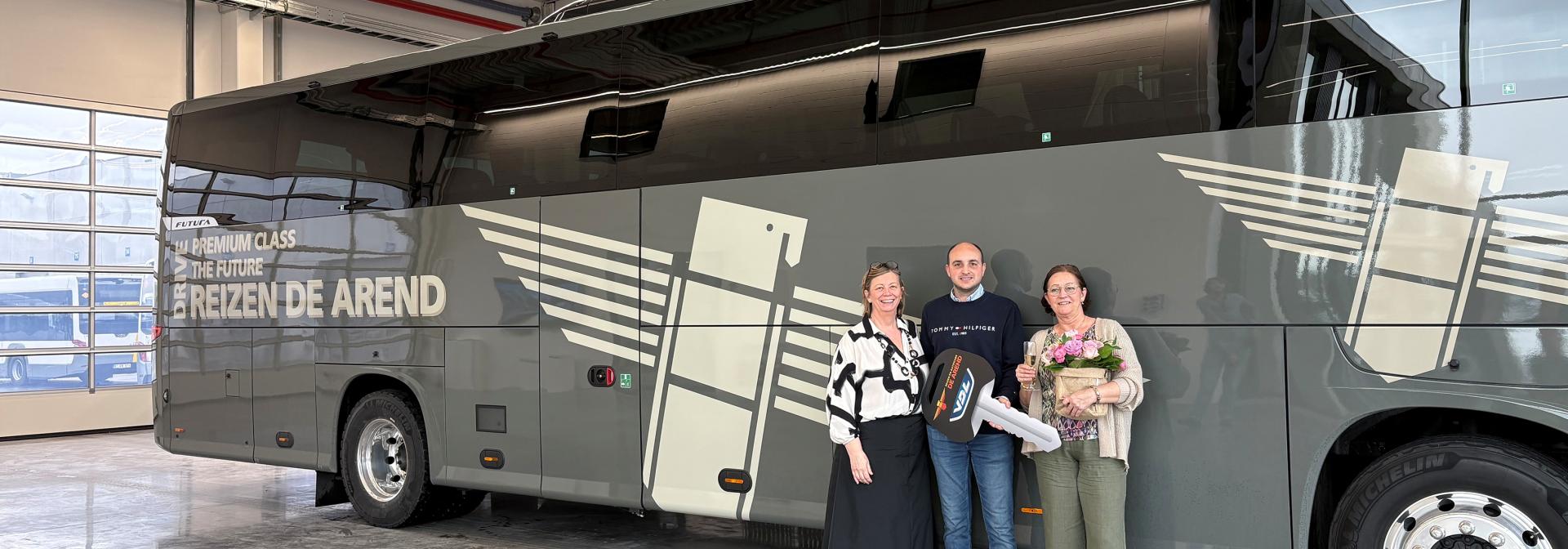 Three people stood by a bus, one is holding a massive key