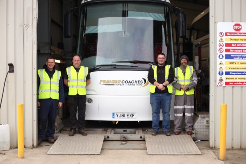 4 people in high vis stood next to a coach