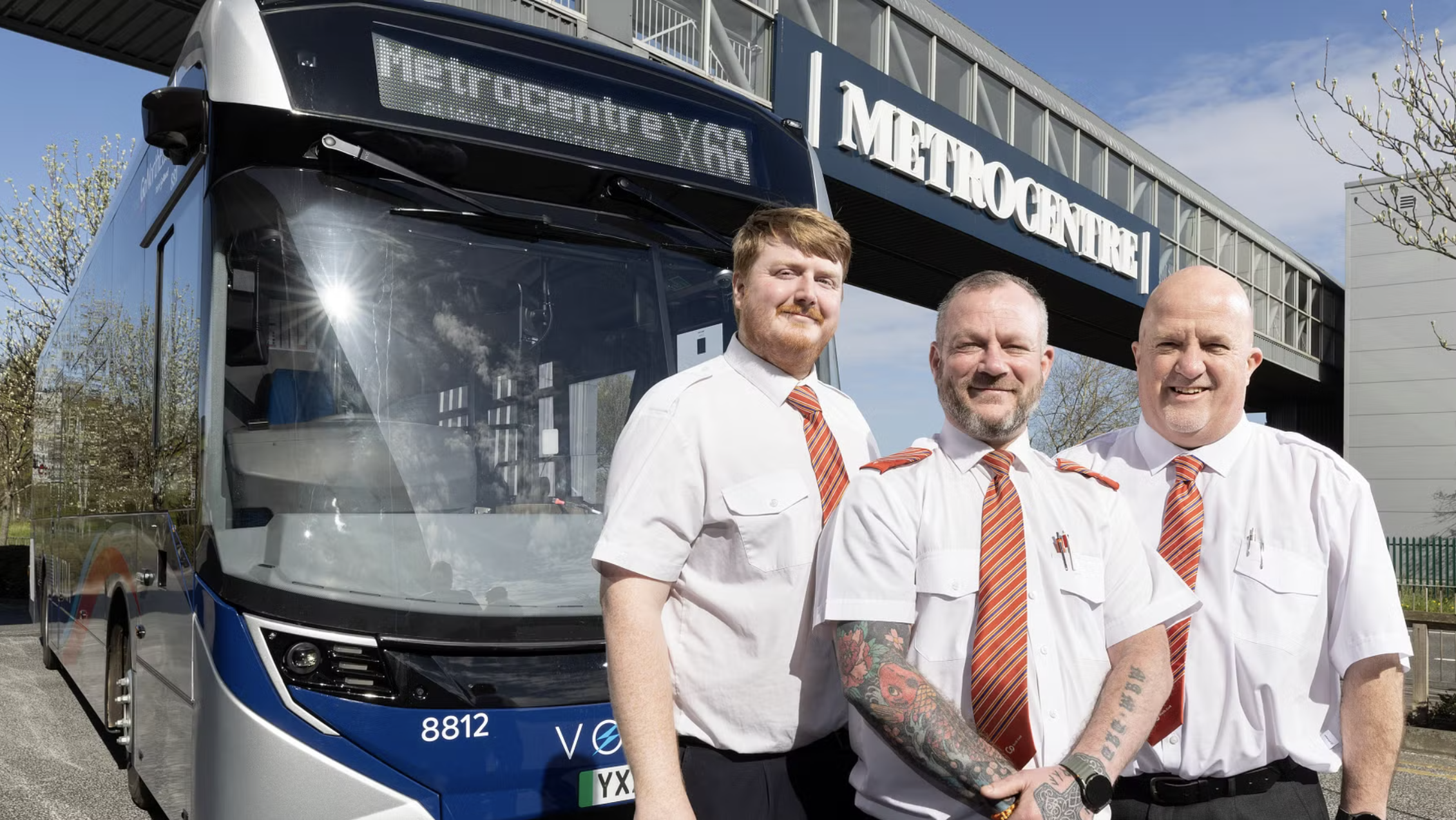 Three people stood by a bus