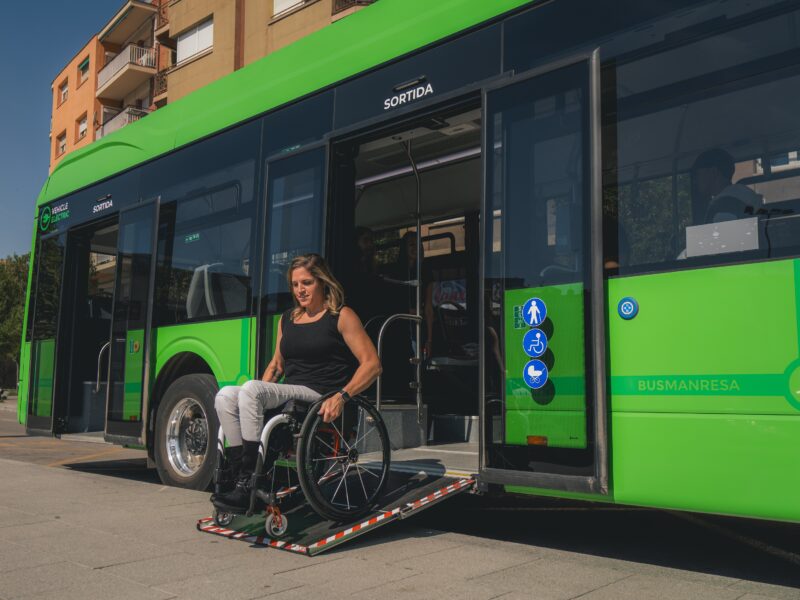 Person in wheelchair using an Accessibility ramp attached to green bus