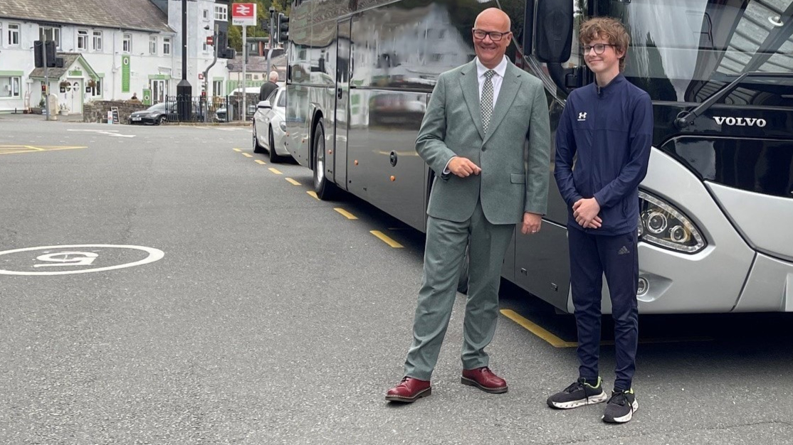 Young person with Deputy Minister for Transport Mark Hooper, both are stood by a bus