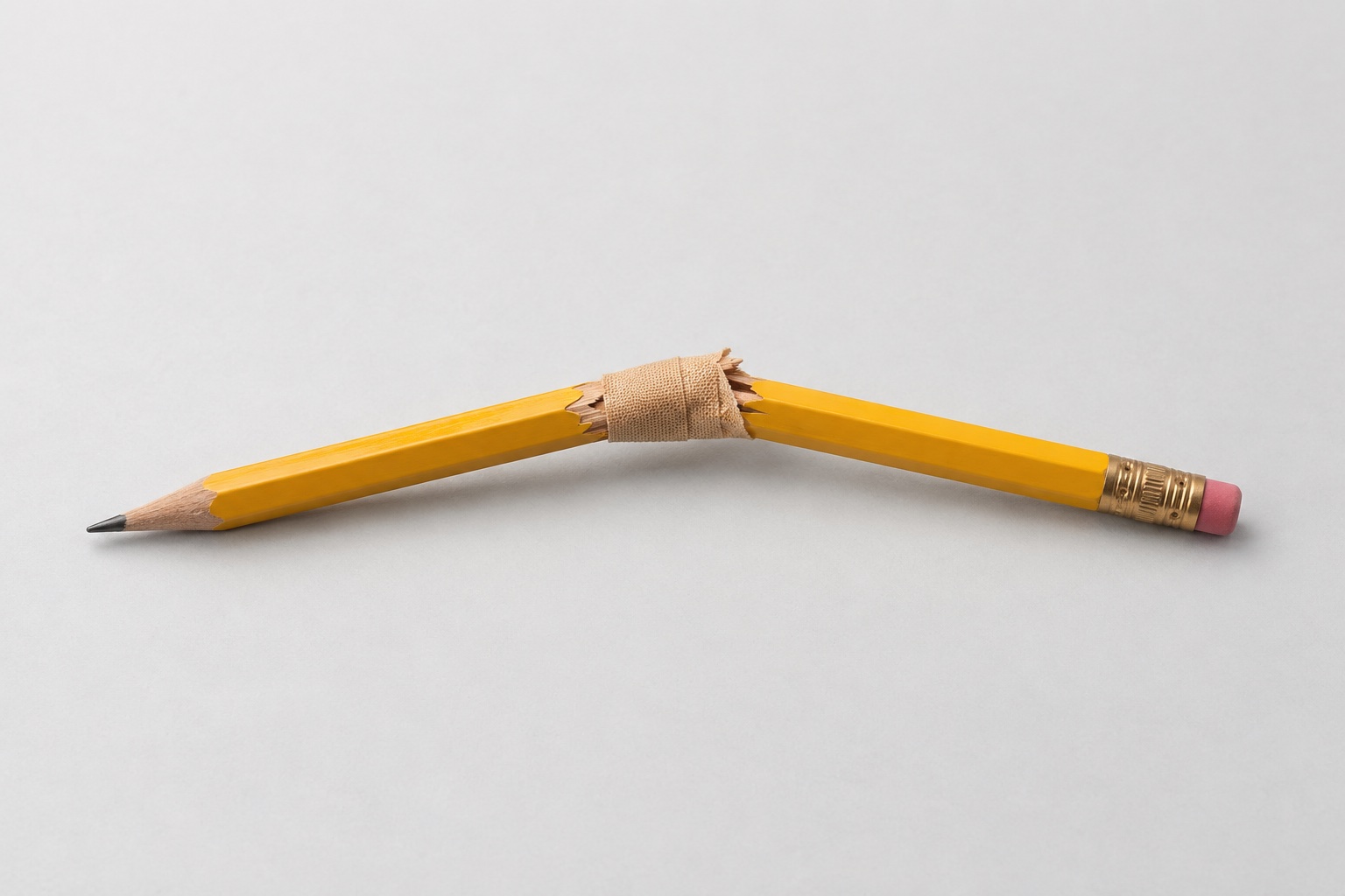 Broken yellow pencil held together with a sticking plaster