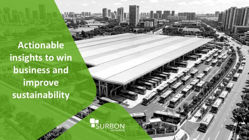 Aerial view of a large bus depot with rows of buses parked under a long canopy, with Surbon Consulting branding