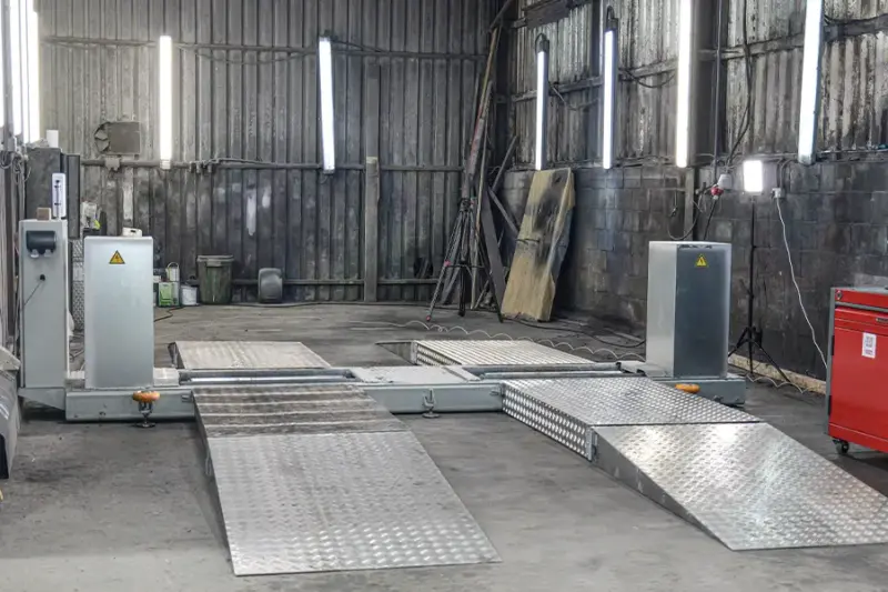 Mobile roller brake tester with aluminium ramps set up on the floor of a vehicle workshop